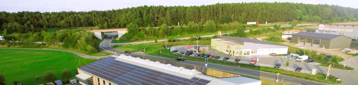 Blick über das Gewerbegebiet Wilting mit dem Firmengebäude und der Photovoltaikanlage auf dem Dach